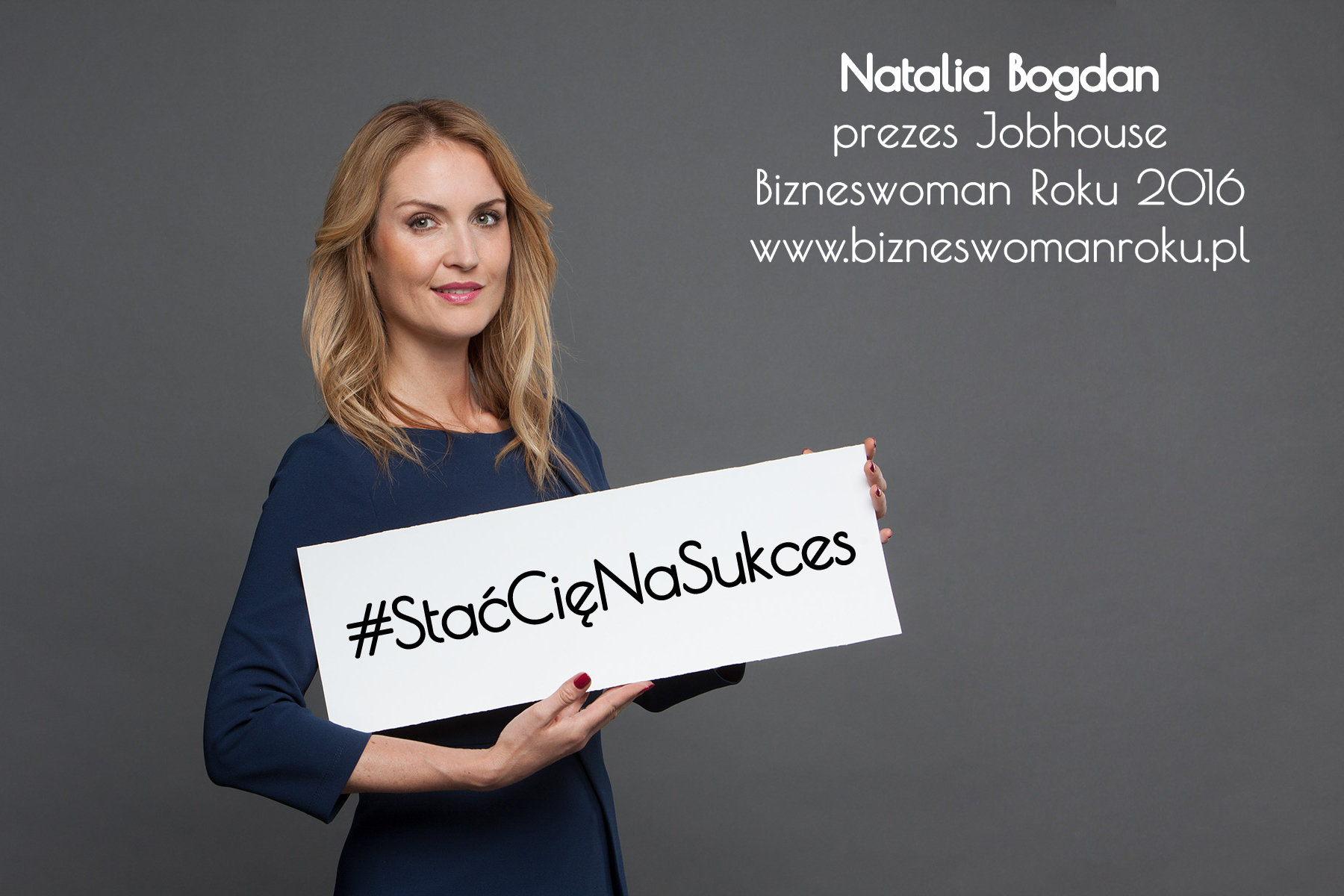 Na zdjęciu Natalia Bogdan w granatowej sukience, trzymająca w ręce szyld # StaćCięNaSukces. W prawym górnym rogu napis: Natalia Bogdan, prezes Jobhouse, Bizneswoman Roku 2016 i strona internetowa: www.bizneswomanroku.pl